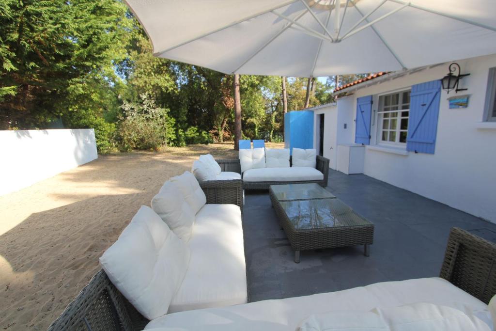 奧雷龍聖喬治的住宿－La Villa Oleron，庭院配有白色家具和雨伞。