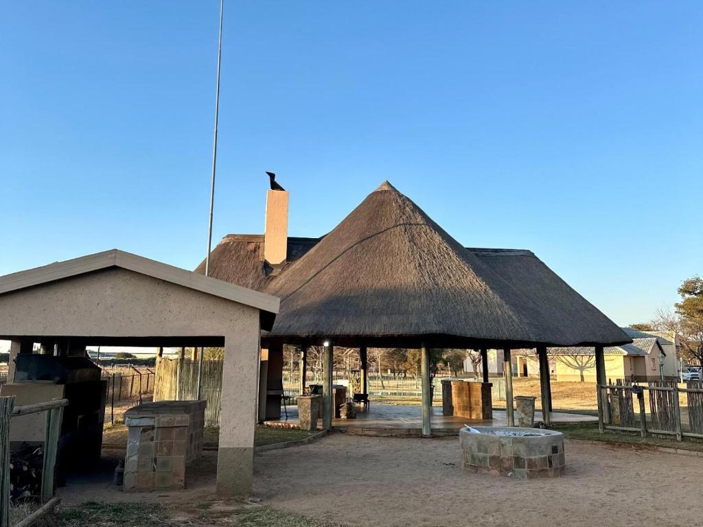een gebouw met een rieten dak met een veld op de achtergrond bij Carousel Eco Estate in Temba