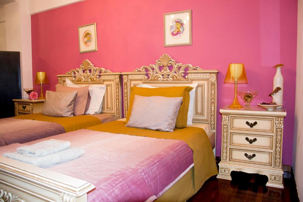1 dormitorio con 2 camas y pared de color rosa en Enallio Luxury Apartments, en Nauplia