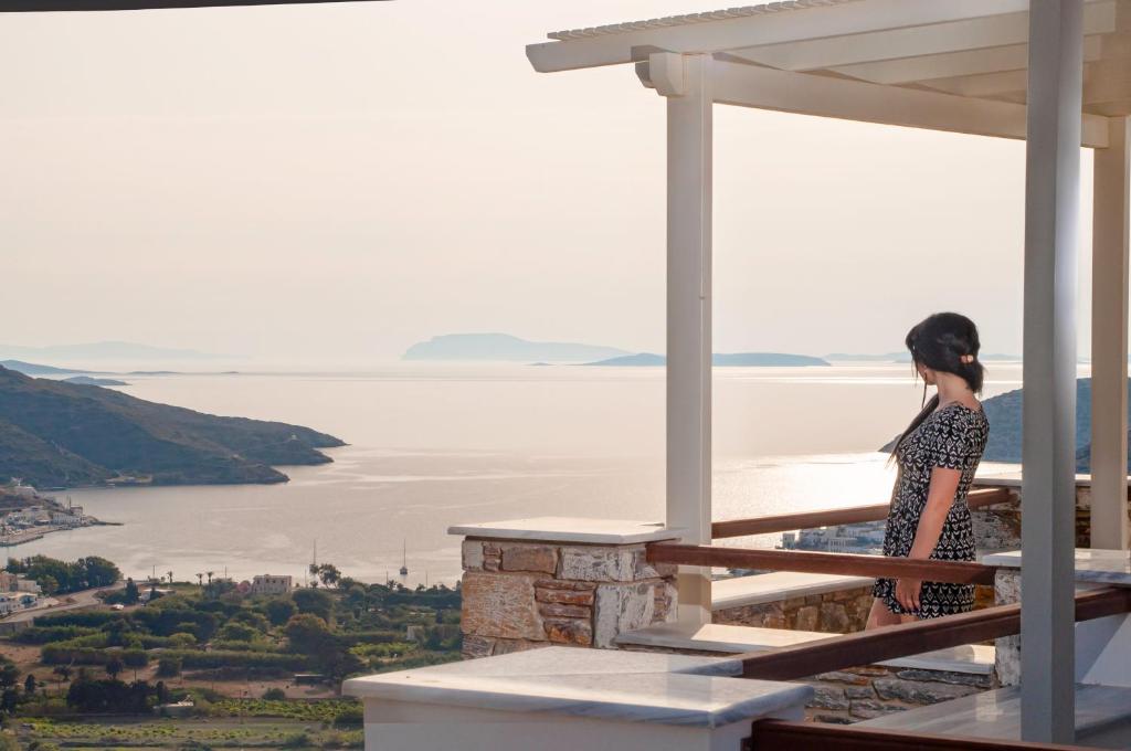 a woman standing on a balcony looking out at the water at Skopelitis Village in Katapola