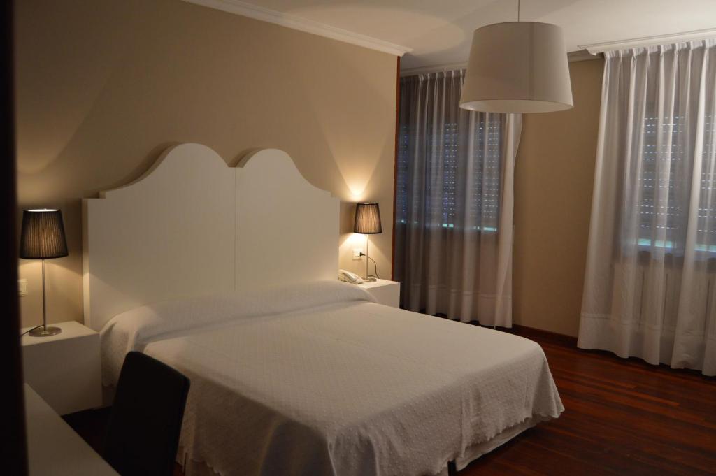 a bedroom with a white bed and a large window at Hotel Chancelas in Chancelas