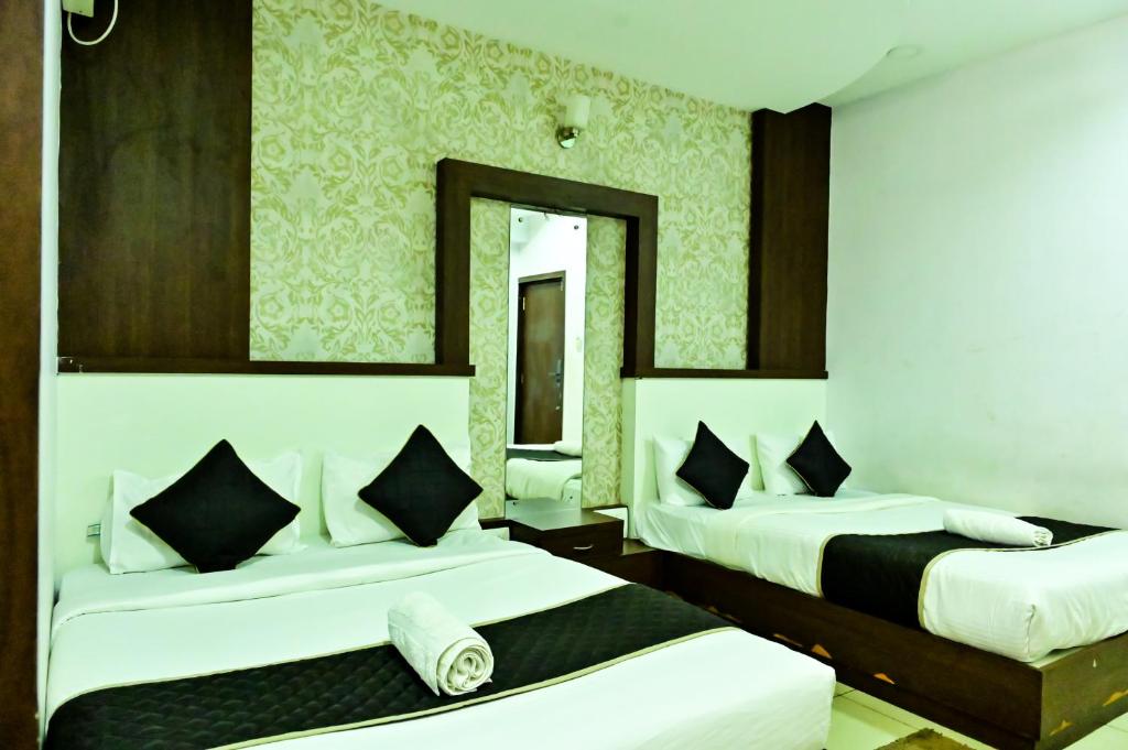 a hotel room with two beds and a mirror at Townhouse Nisarga in Chikmagalūr