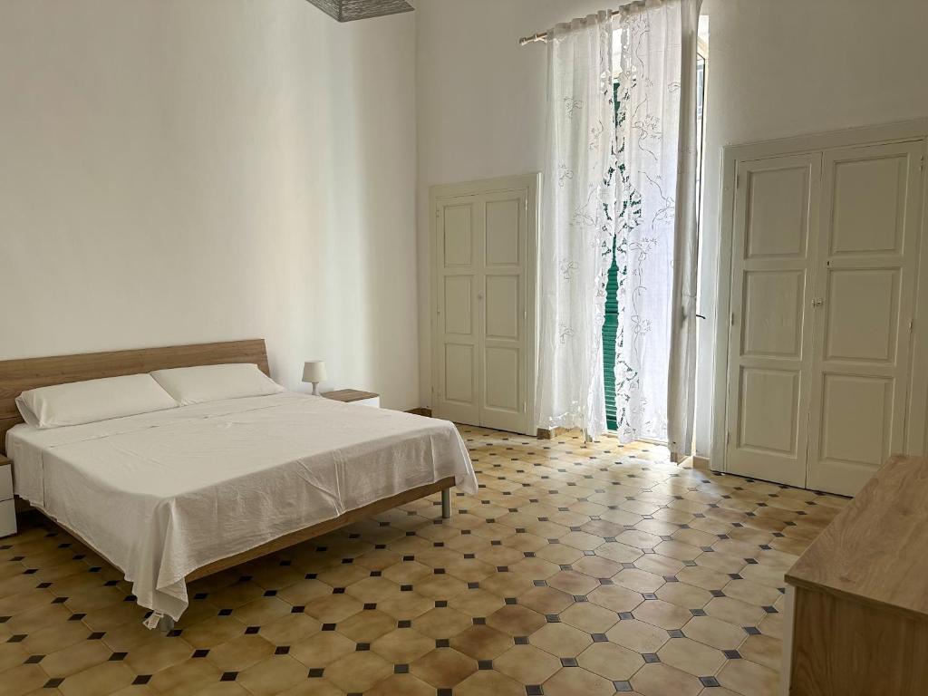 ein weißes Schlafzimmer mit einem Bett und einem großen Fenster in der Unterkunft Dimora Immacolata in Castellana Grotte