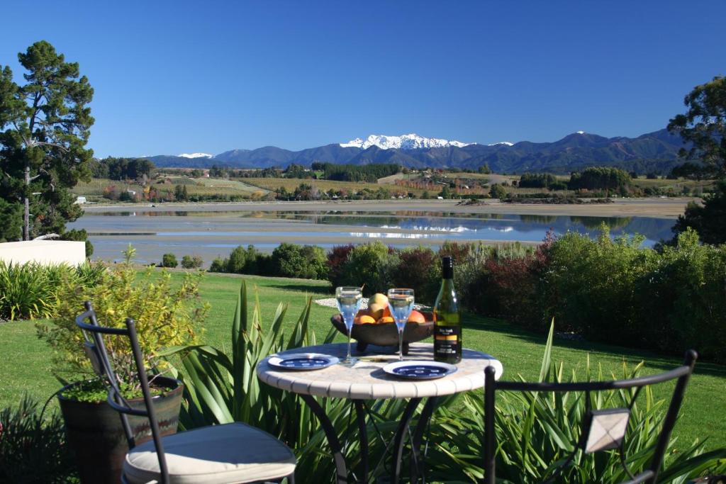 uma mesa com uma garrafa de vinho e um copo em Almyra Waterfront Accommodation em Tasman