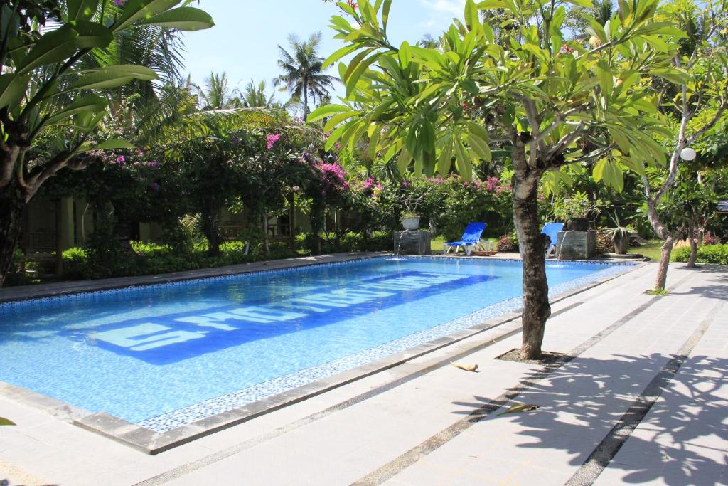 a swimming pool with a tree in the middle at Vico hotel in Nusa Dua