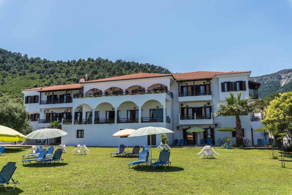 a large building with chairs and umbrellas in the grass at Hotel Sylvia in Koinyra
