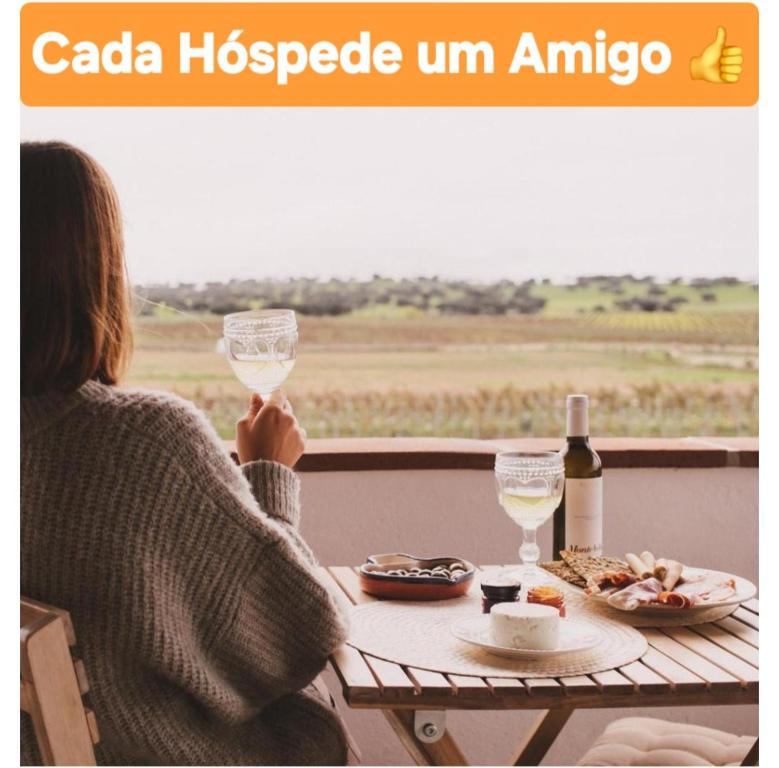 Eine Frau, die mit einem Glas Wein am Tisch sitzt. in der Unterkunft Casa Coração Alentejano- Casas com EnCanto in Reguengos de Monsaraz