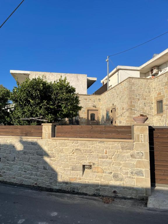 un muro de contención de piedra con una valla de madera en Casa Maria, en Gramvousá