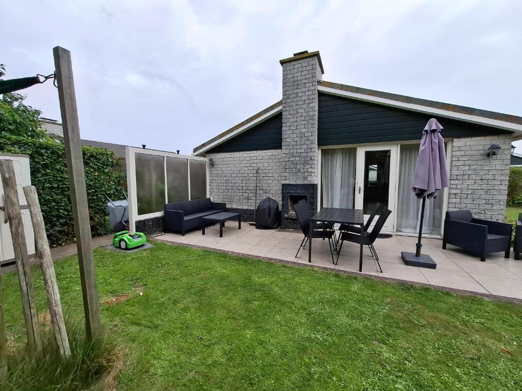 a patio with chairs and a table in a yard at Cosy Petten, Family only in Petten