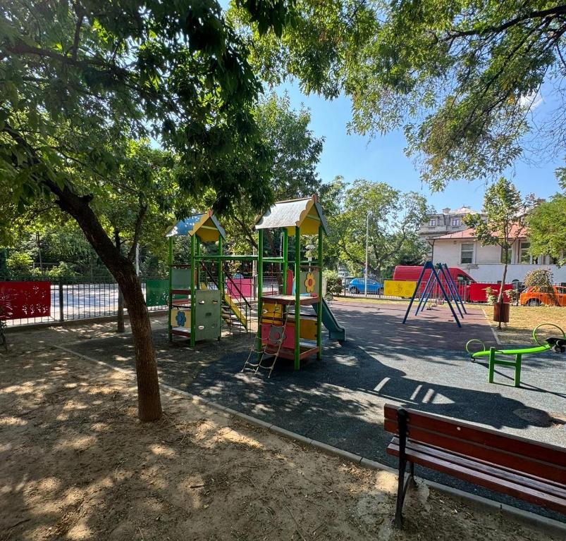 a park with a playground with a bench and a tree at Cismigiu Bucharest Central 2 bedrooms Apartment in Bucharest