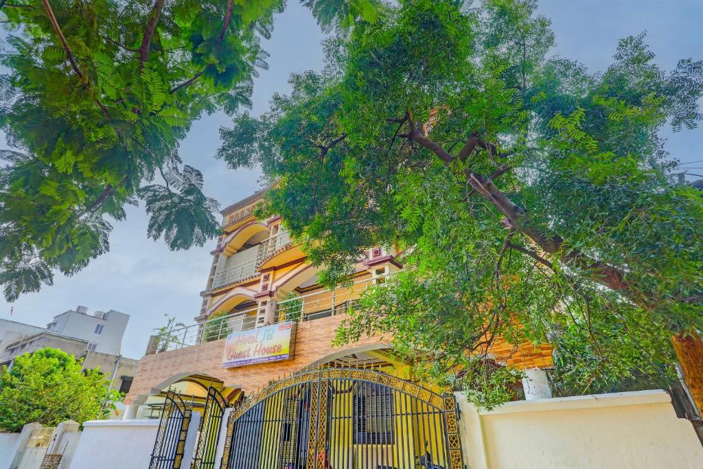 a yellow building with a gate and a tree at Hotel O Dibya Guest House in Bhubaneshwar