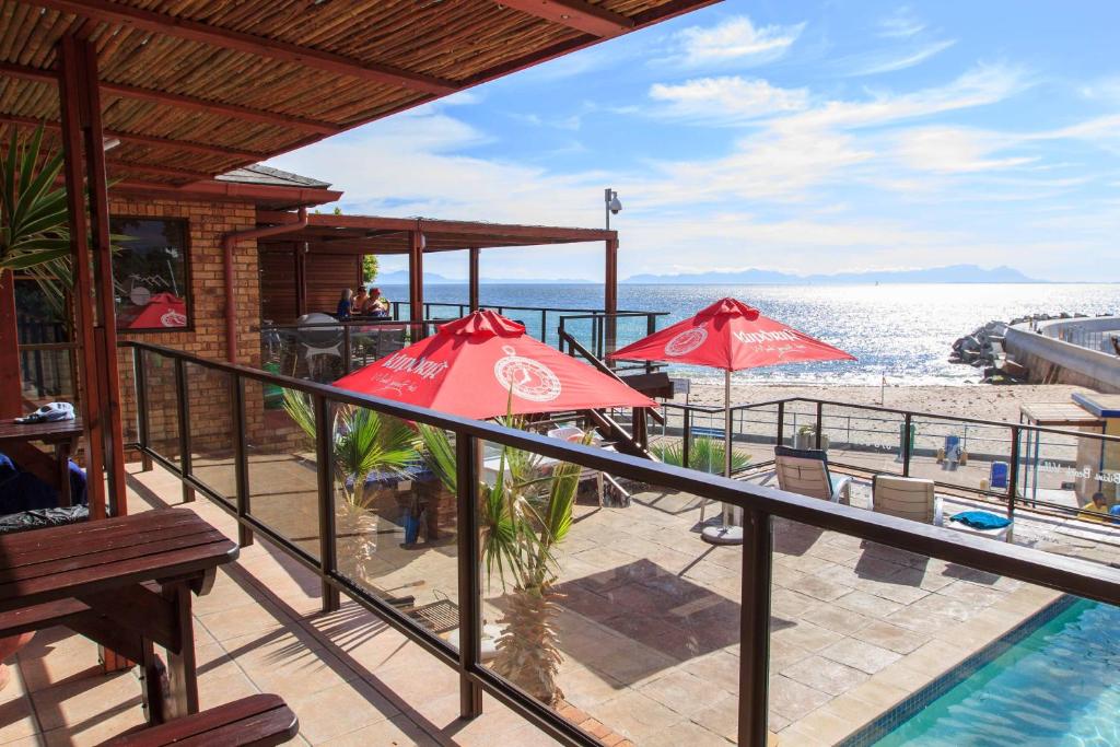 balkon z czerwonymi parasolami i basenem w obiekcie Bikini Beach Villas w mieście Gordonʼs Bay