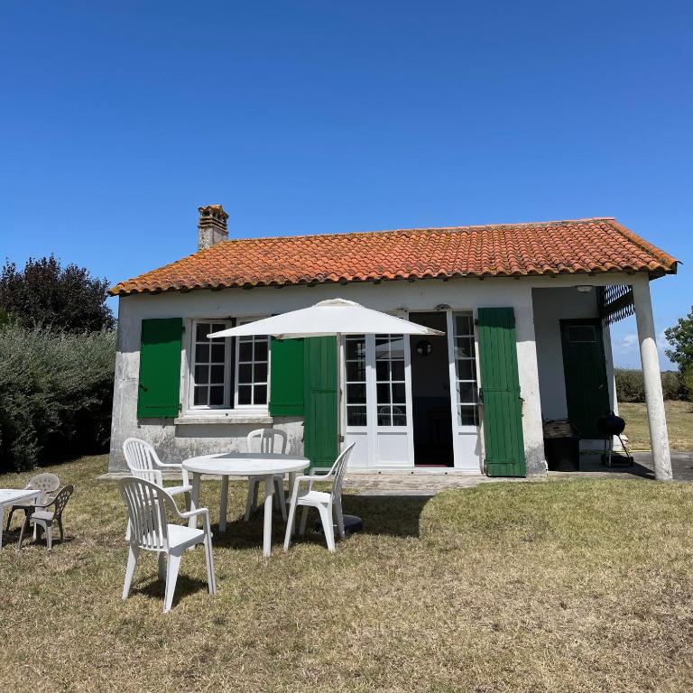 a table with chairs and an umbrella in front of a house at Maison sur la Mer - FrontSea in Angoulins-sur-Mer