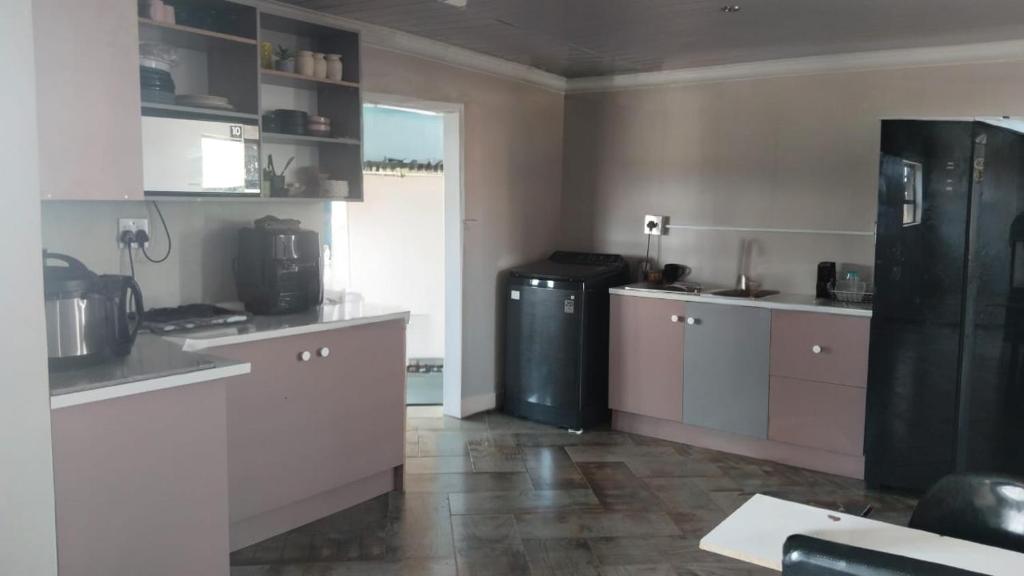 a kitchen with white cabinets and a black refrigerator at Self service catering cute and comfy nestled in the Center of Lenasia in Lenasia