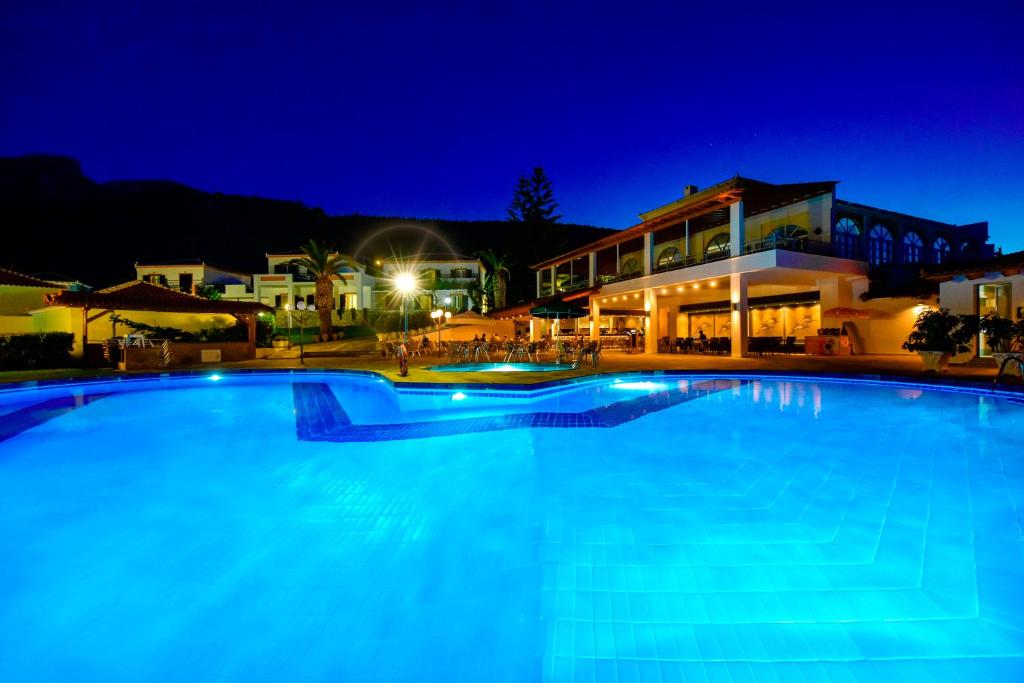 a large blue swimming pool at night at Arion Hotel in Kokkari