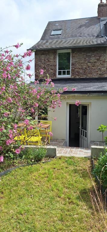 un banc jaune devant une maison avec des fleurs roses dans l'établissement Le Galion, maison avec jardin et parking, à Saint-Valery-sur-Somme