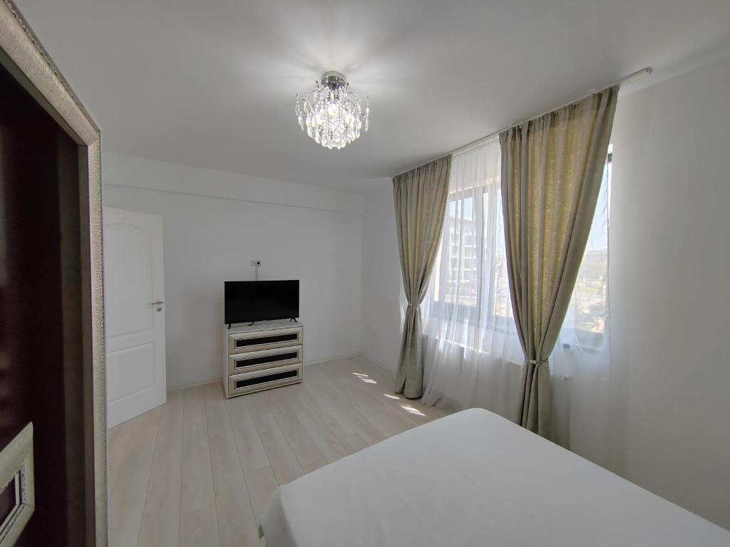 a white bedroom with a bed and a television at DML Apartment in Mamaia Nord