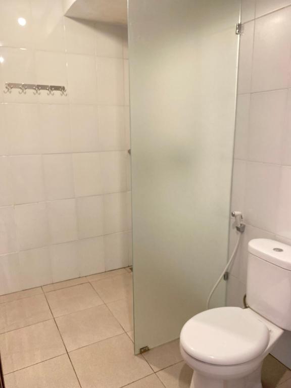 a bathroom with a toilet and a glass shower door at Uma Sari Amertha Homestay in Ubud