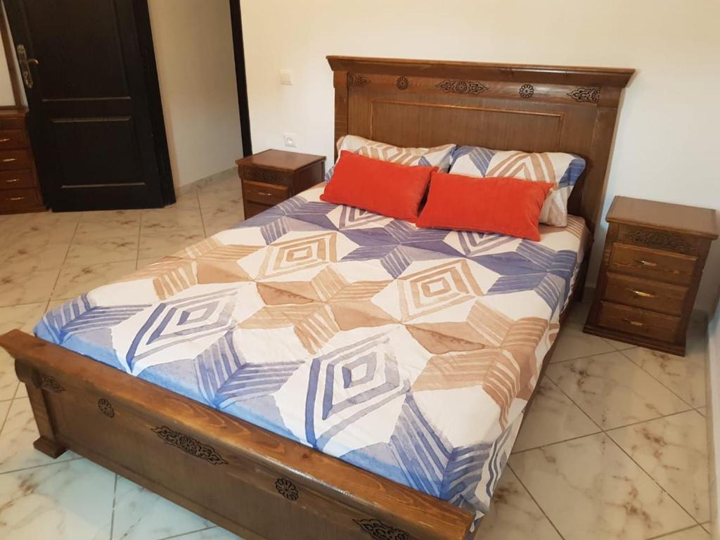 ein Bett mit zwei roten Kissen darauf in der Unterkunft Appart à Martil in Martil