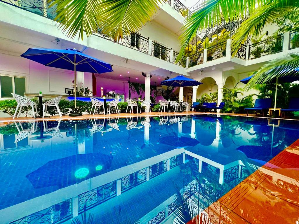 a swimming pool with chairs and umbrellas in a building at Pride Villa Cambodia in Phnom Penh