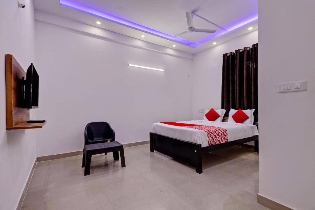 a bedroom with a bed and a black chair at Hotel O Maruthi Paradise Netaji Udyanavana Park in Bengaluru