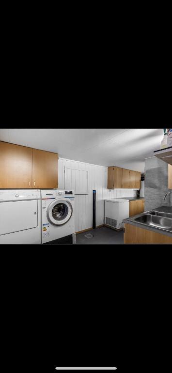 a kitchen with a washing machine and a sink at Hytte nært lutsivannet in Sandnes