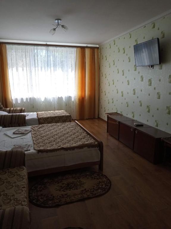 a bedroom with two beds and a tv on the wall at Затока жилье центр въезд со стороны Белгород-Днестровского in Zatoka