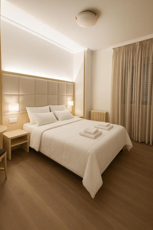 a bedroom with a large white bed and a window at Elara MSuites in Viveiro
