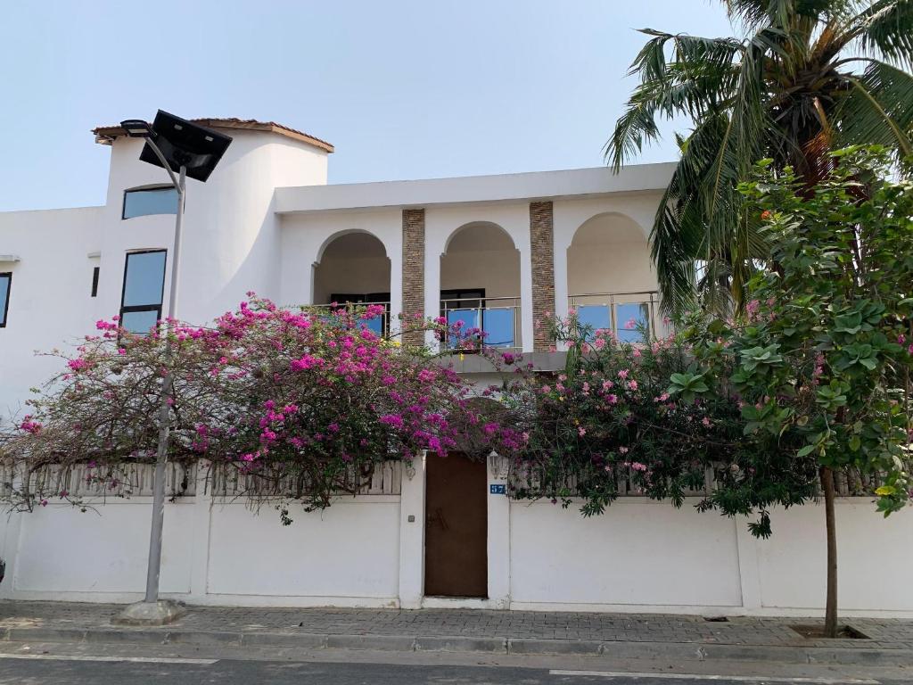 a white building with pink flowers on it at Maison calme et fleurie in Cotonou