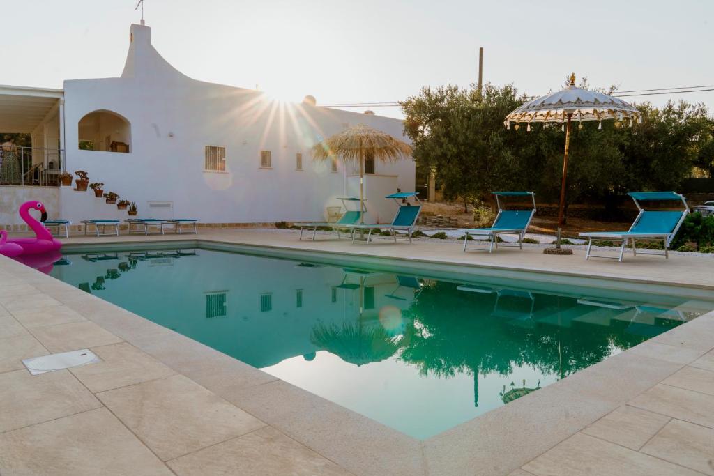 オストゥーニにあるLa Terrazza sugli Ulivi - con PISCINA PANORAMICAの青い椅子と建物のあるプール