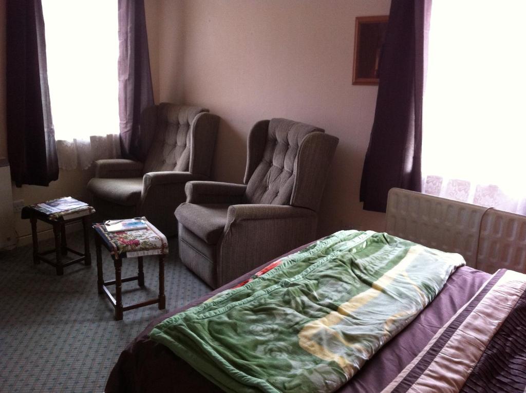 a bedroom with two chairs and a bed and a bed and a chair at 48 Harper Road Beckton Shared in East Ham