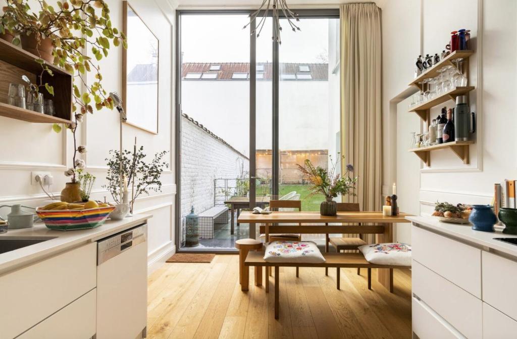 a kitchen with white cabinets and a table and a window at Cozy Room with Garden in Brussels