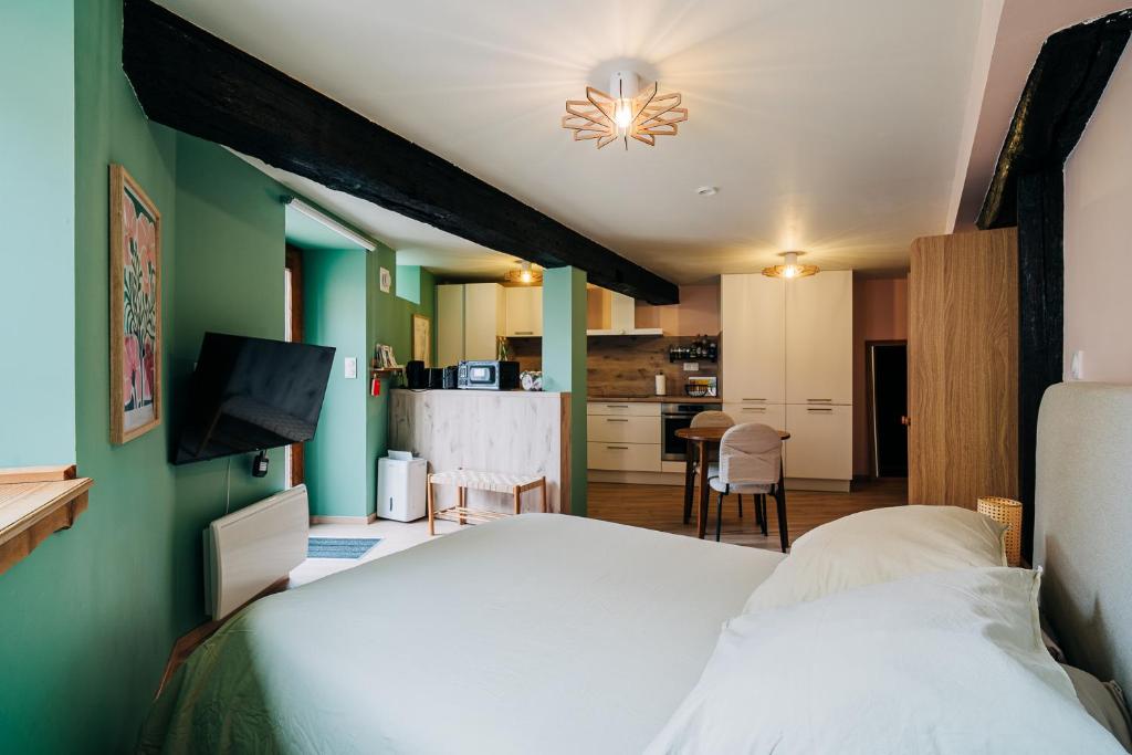 a bedroom with a white bed and a kitchen at Suite Vieille Ville - Calme et Cosy - Parking gratuit in Sélestat