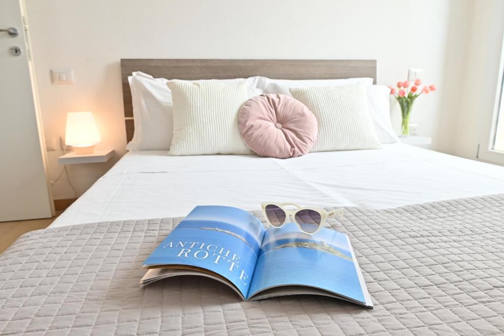 un livre avec une paire de chaussures et un magazine sur un lit dans l'établissement IzzHome Oasis, à Pula