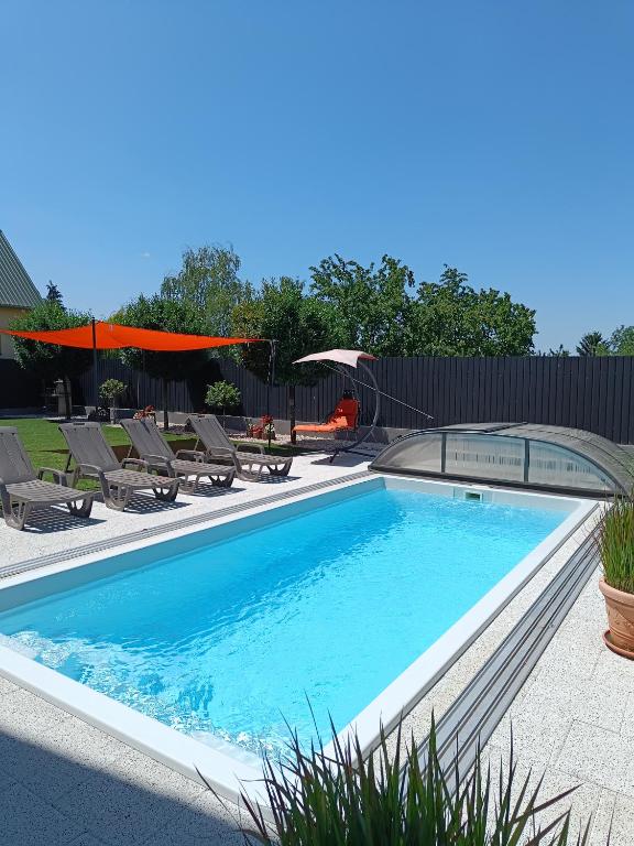 a swimming pool with chairs and umbrellas in a yard at Zöld Apartmanház in Balatonboglár