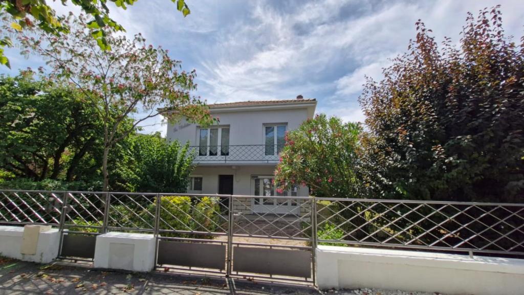 une maison blanche derrière une clôture dans l'établissement Saint Georges de Didonne - MAISON à proximité du centre et de la plage, à Saint-Georges-de-Didonne