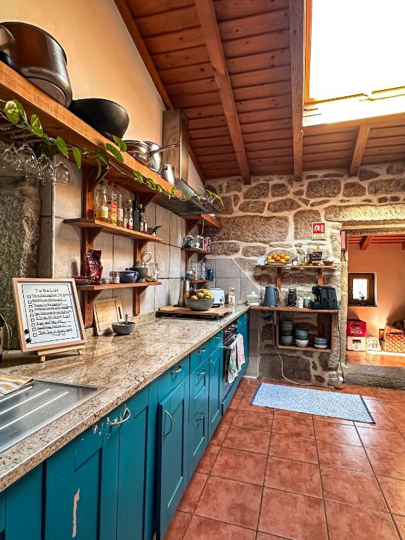 a kitchen with blue cabinets and a stone wall at Pilgrims Rest - Vila Nova de Cerveira - Hostel - Albergue - AL in Vila Nova de Cerveira