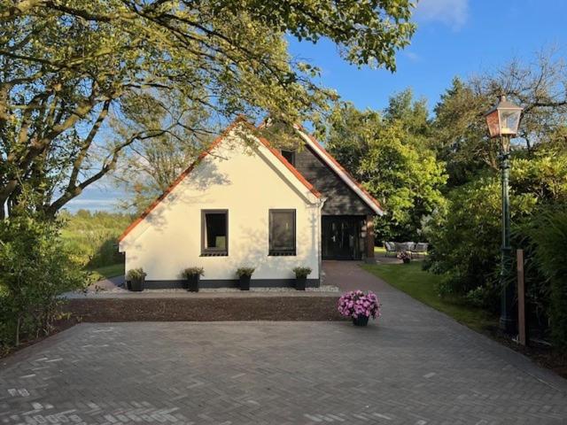 a small white house with flowers in front of it at De Geluksbrenger in Spanga