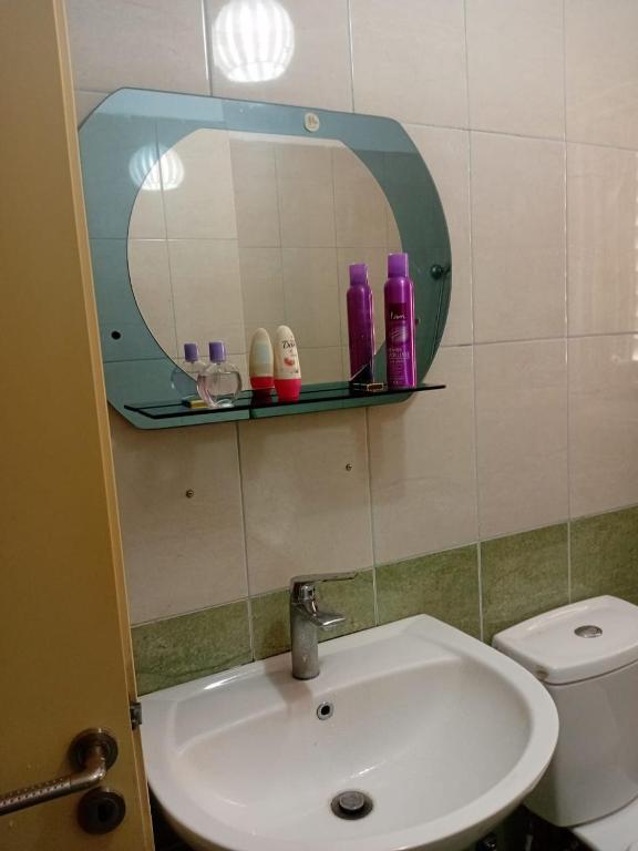 a bathroom with a sink and a mirror and a toilet at Qetesia Apartment in Shkodër