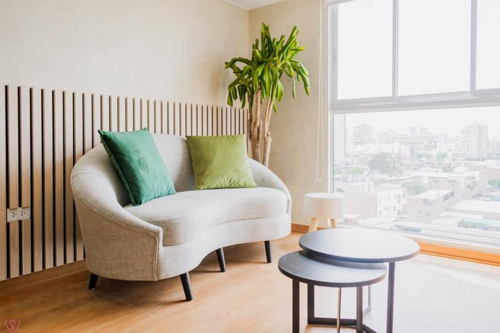a living room with a white chair with green pillows at Engaging 2BR rooftop view in Barranco in Lima