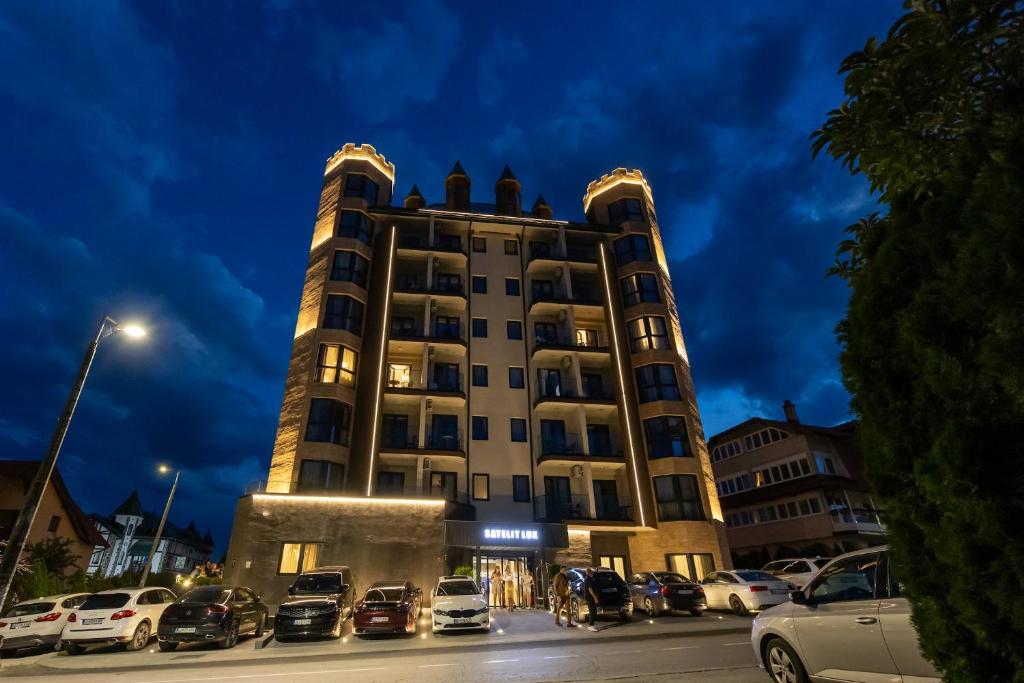 Satelit Lux Zlatibor - SPA & half board by Satelit Resorts في زلاتيبور: مبنى شاهق به سيارات متوقفة في موقف السيارات