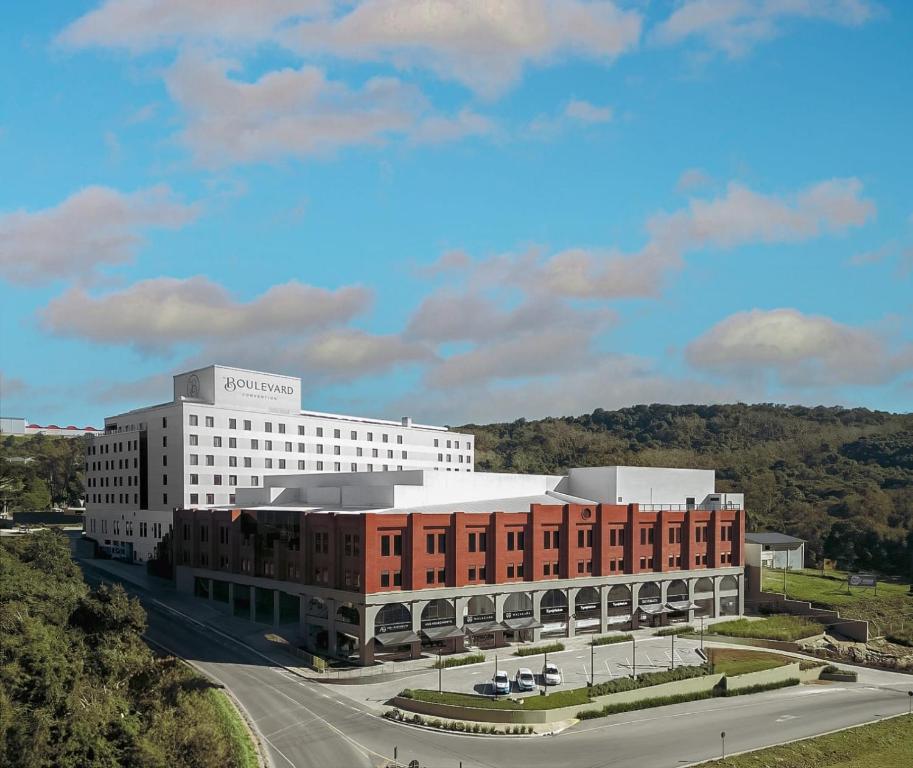 本图贡萨尔维斯Plaza Hotel & Boulevard Convention - Vale dos Vinhedos的前面有一条路的白色大建筑