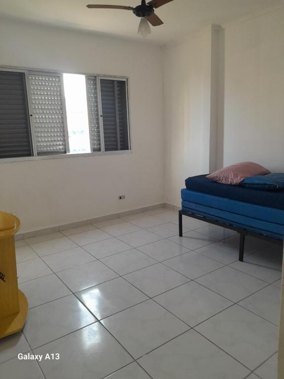 大普拉亚Lindo apartamento Vila Mirim的一间卧室设有蓝色的床和2个窗户。