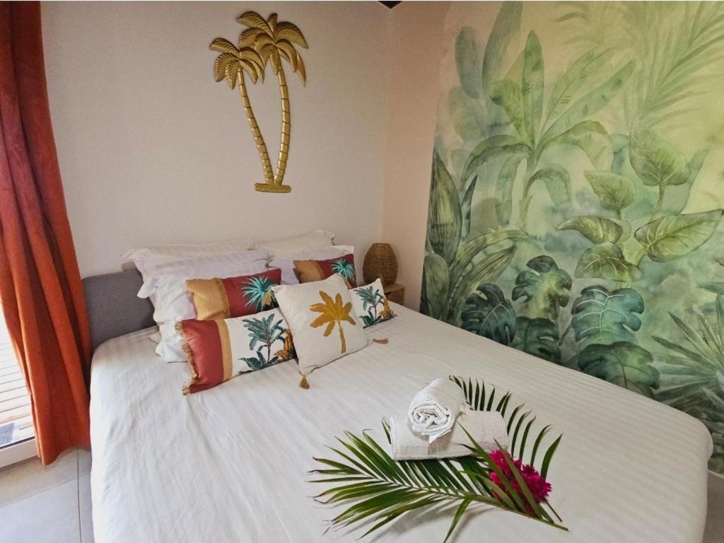 a bedroom with a white bed with colorful pillows at Ti Oasis SEAVIEW, Studio Vue Mer à 150m de la plage in Corps de Garde