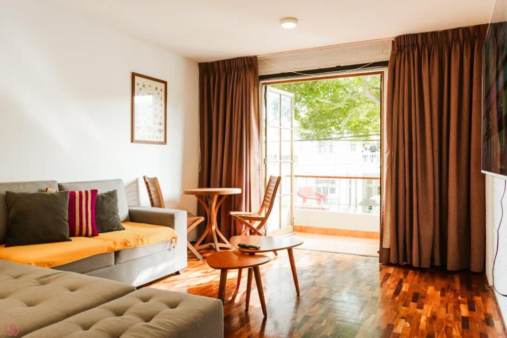 een woonkamer met een bank en een groot raam bij Cozy 2BR Relaxing Vibe in Lima