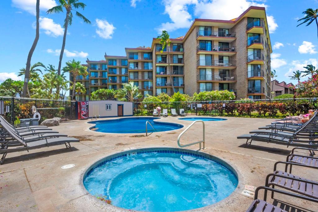 Una piscina con sillas y un edificio. en Sunset Palms Kihei s Cozy Beach Escape, en Kihei