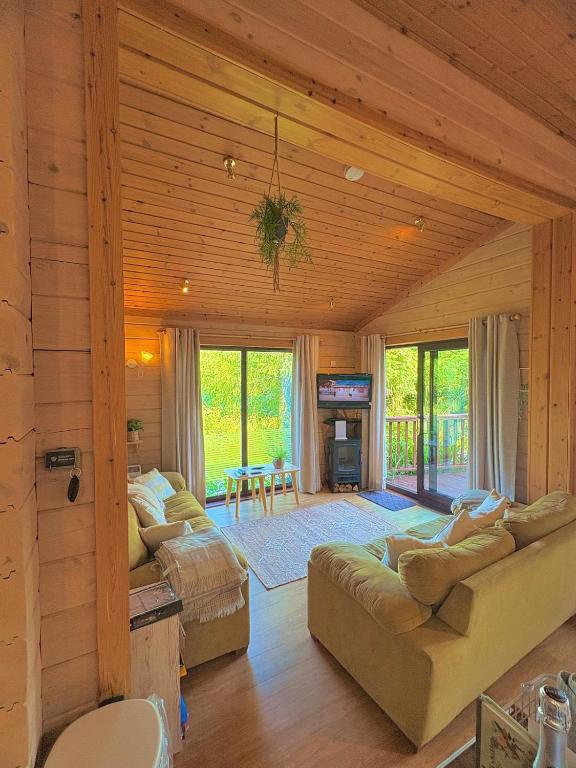 a living room with couches and a tv in a house at Luxury Woodland Lodge near Clovelly & Bude in Woolfardisworthy
