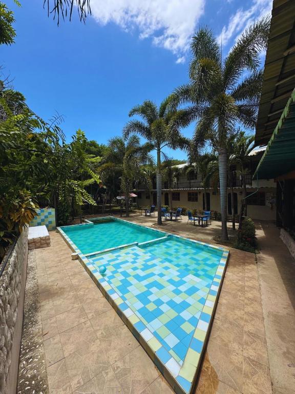 a swimming pool with palm trees in the background at Hostal Luz de Luna in Palomino