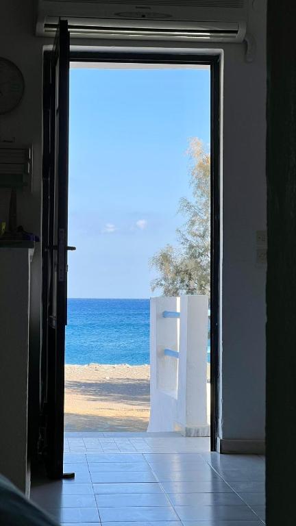an open door to a beach with the ocean at Radiki in Gennadi
