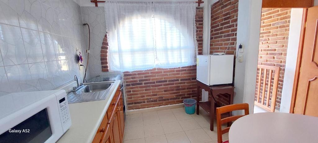 a kitchen with a sink and a brick wall at Hospedaje Migue y Cata y Centro Holístico Kuatlicue in Chignahuapan